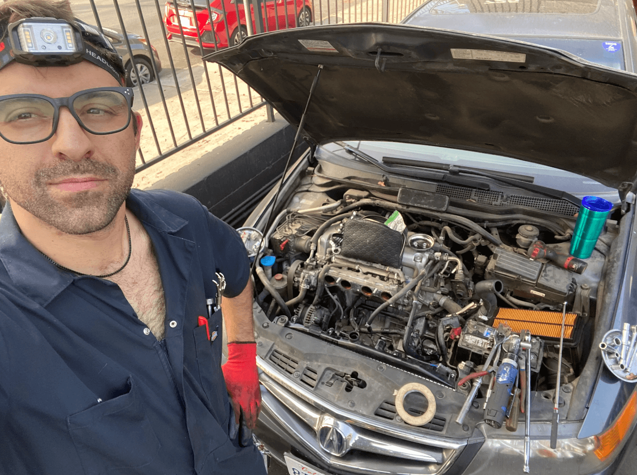 picture of a mechanic in front of a car with the hood up 